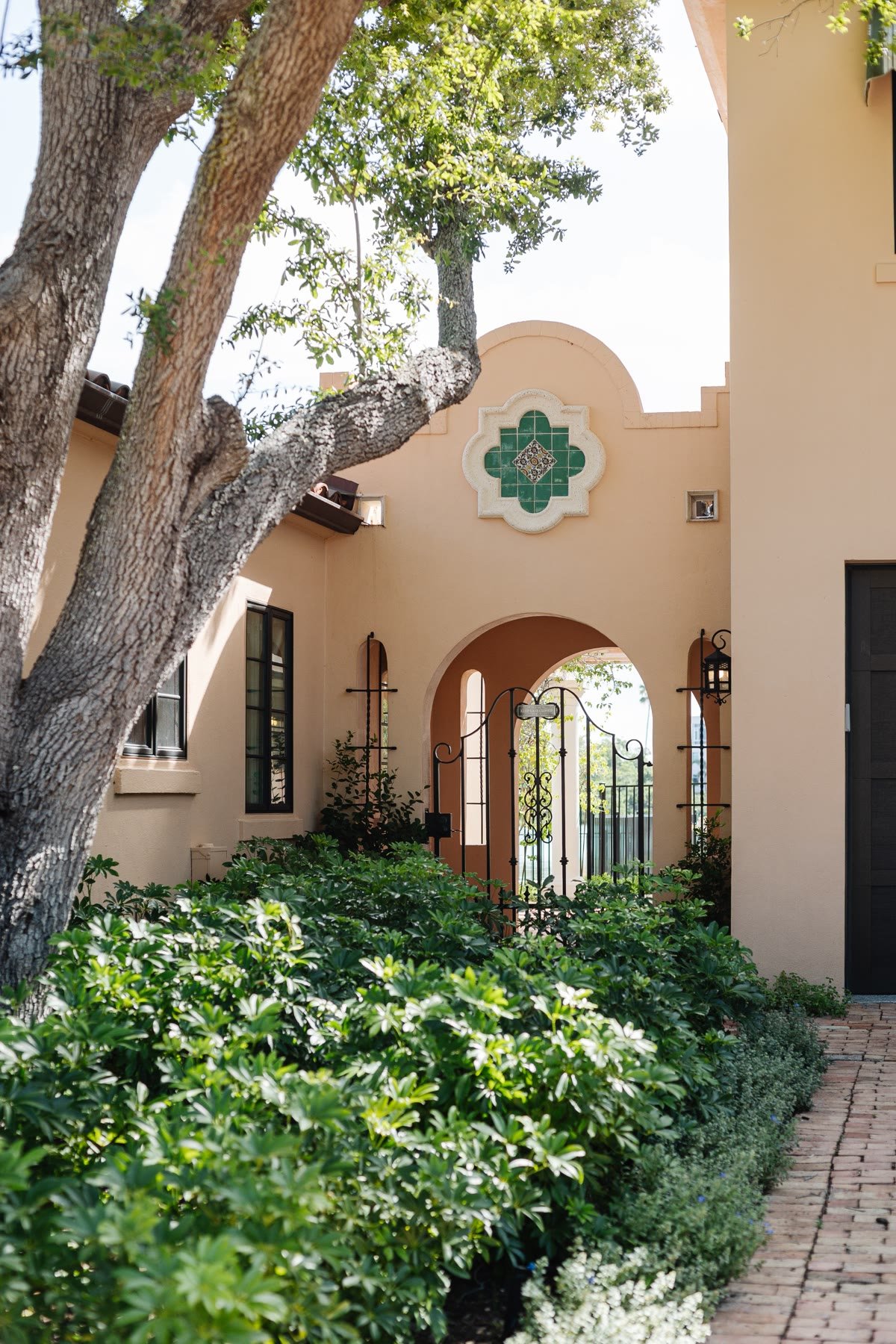 Spanish Mediterranean courtyard with a green tile quatrefoil, an arched gate, and a passage beyond