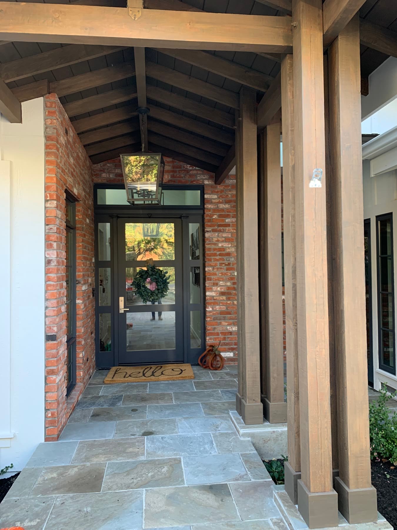 Brick custom-home entry with timber posts, a lantern, and a stone porch