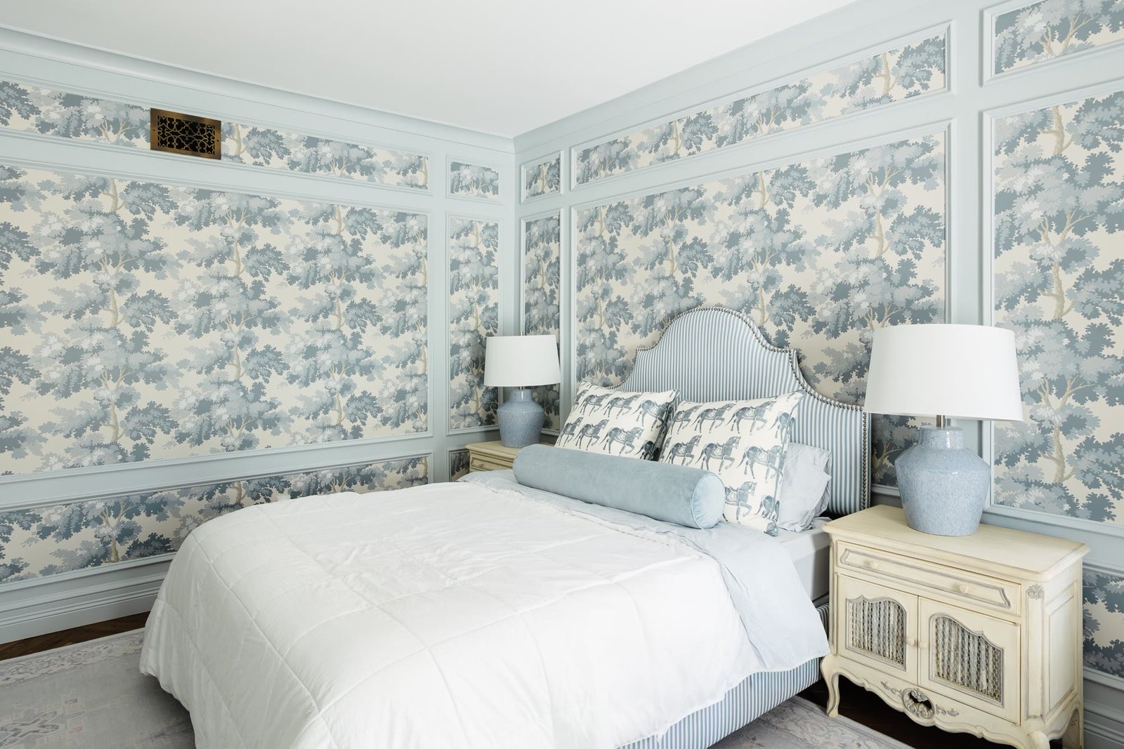 Bedroom with powder-blue paneling, toile wallpaper, and a striped upholstered headboard