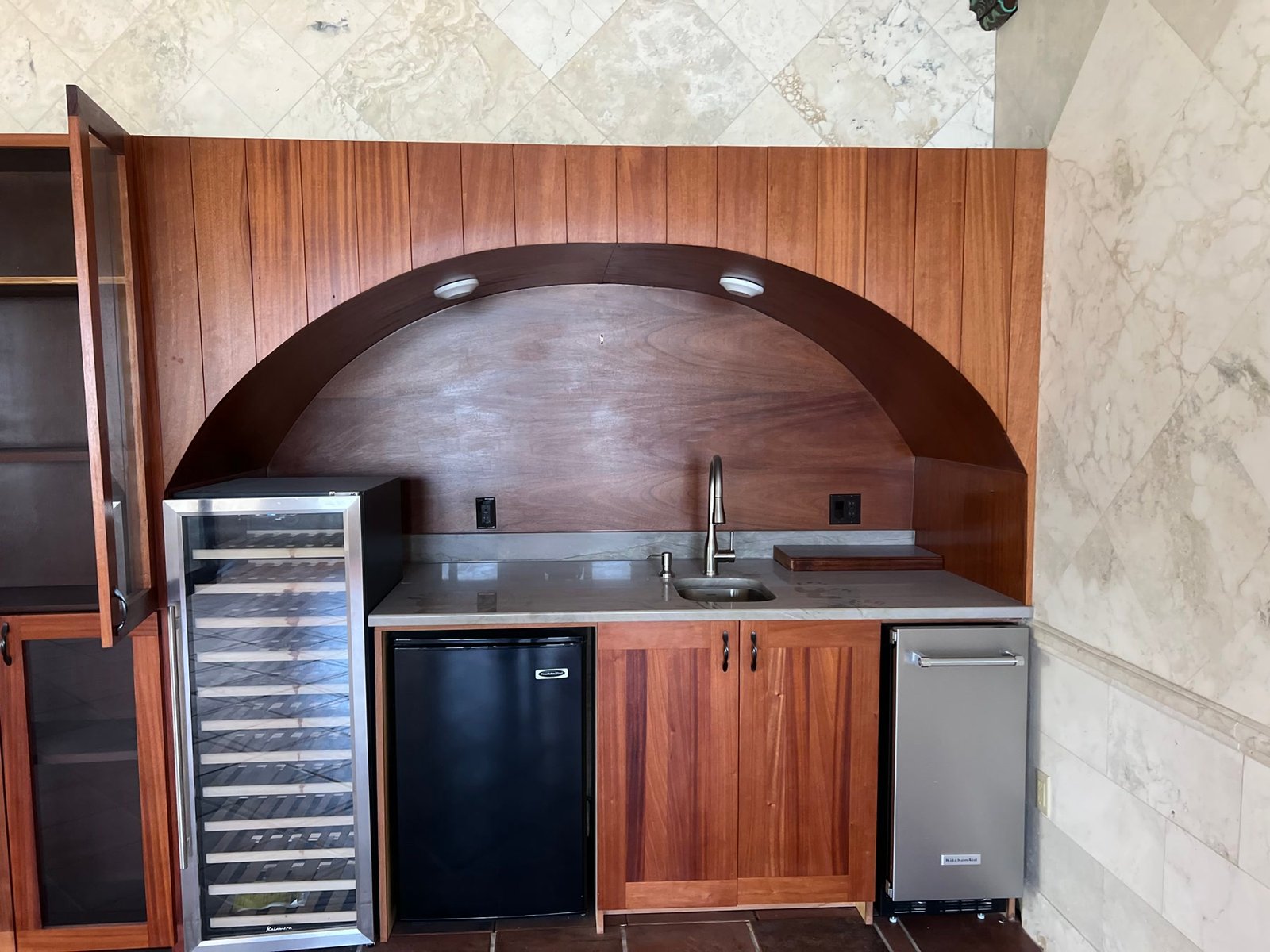 During: mahogany bar millwork with an arched niche, set into the marble walls