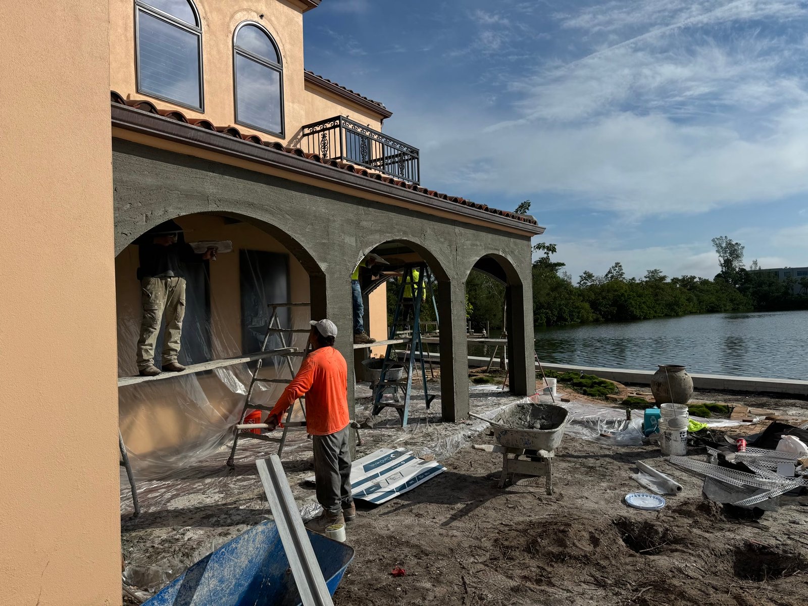 During: stucco going back on the loggia — same house, water still in the picture