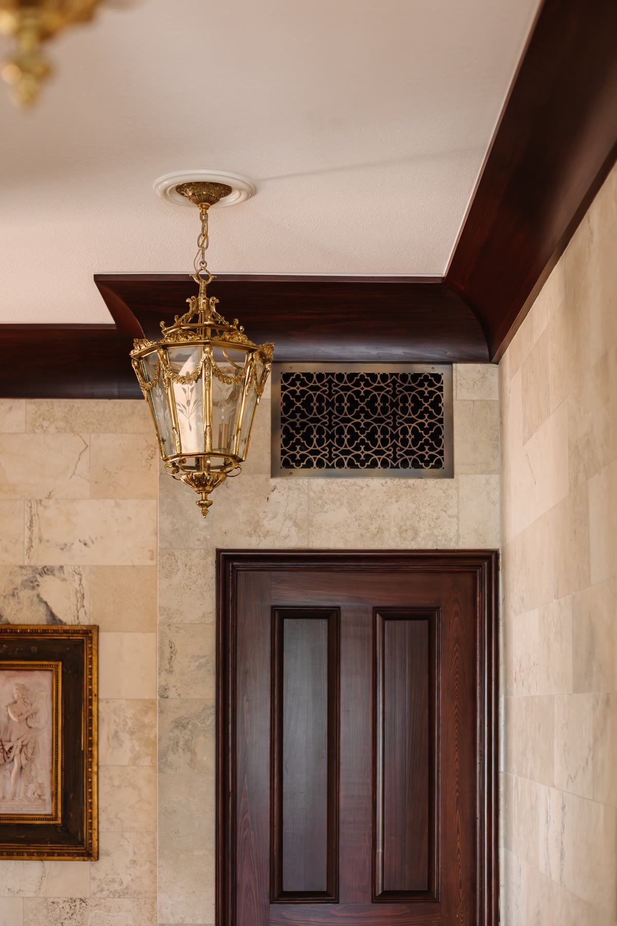 Brass lantern, decorative grille, marble walls, and a mahogany door