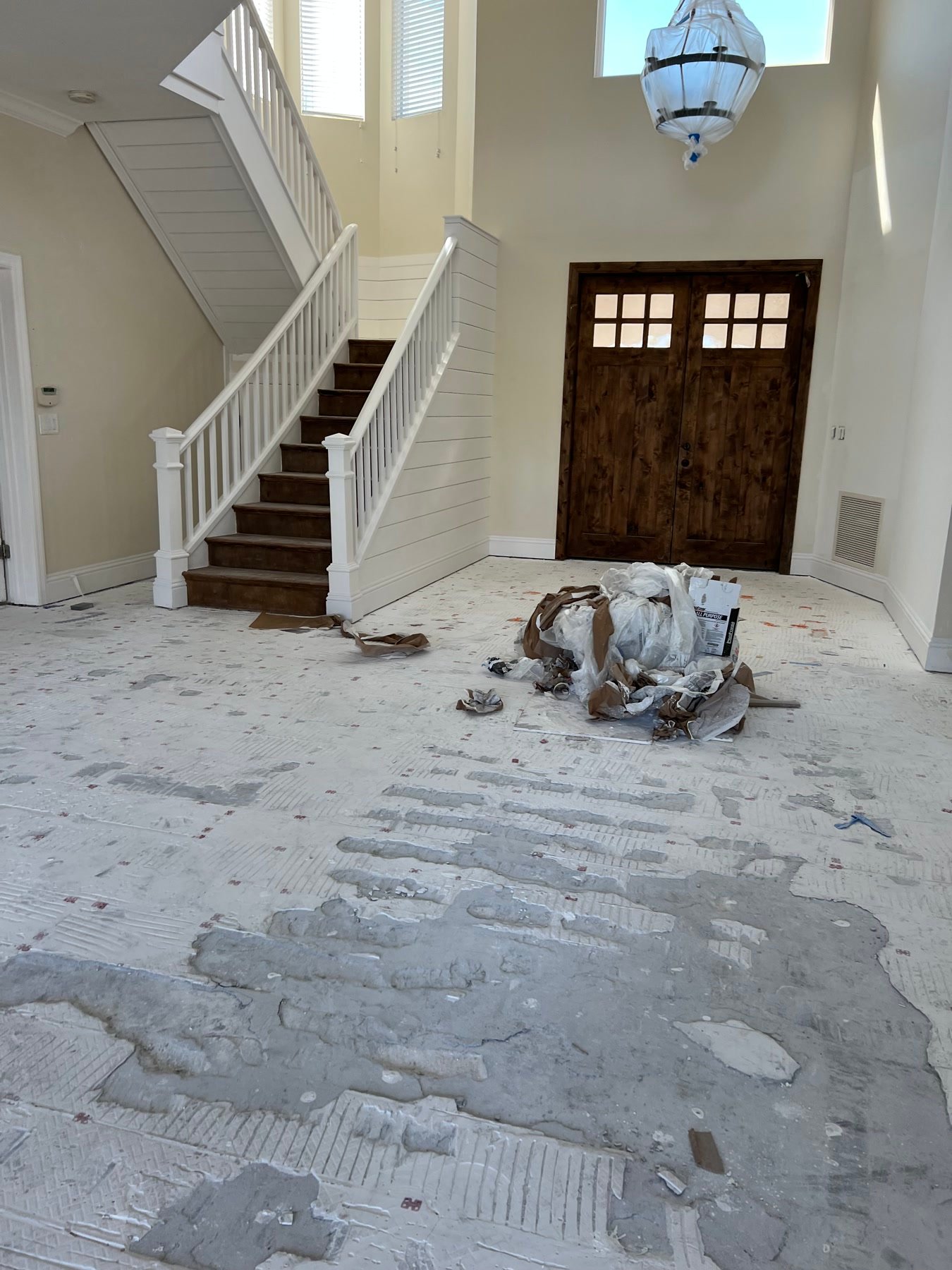 During: foyer floors coming up — staircase, wood doors, and the new millwork language already on the walls