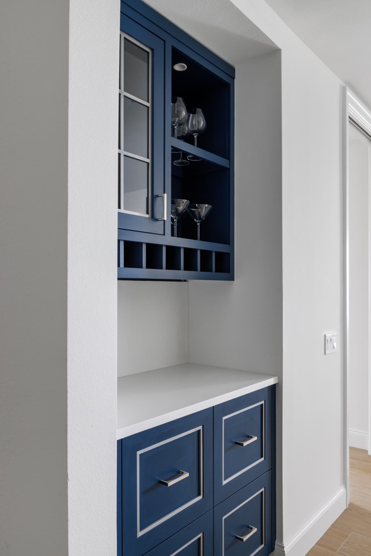Navy wet bar millwork with glass-front cabinets