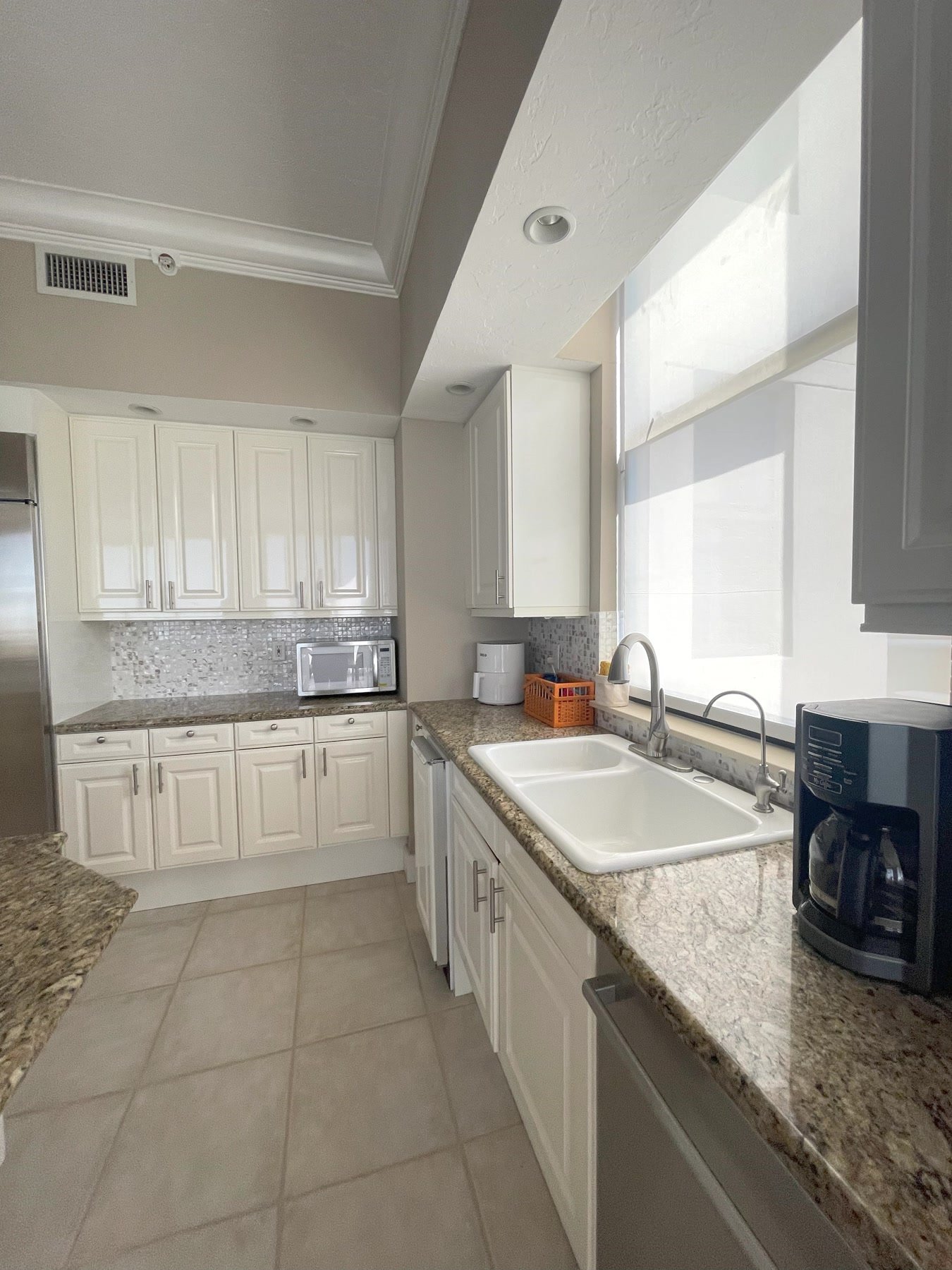 Before: galley kitchen with stock white cabinets, granite, and a mosaic backsplash
