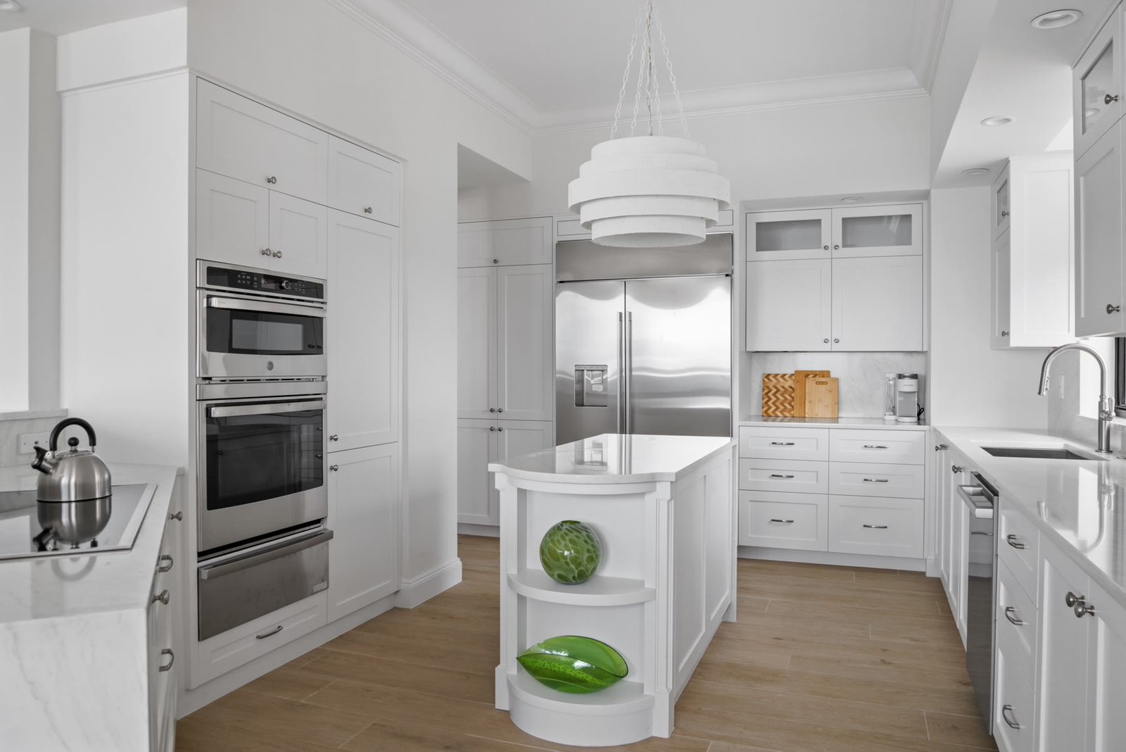 Reconfigured condominium kitchen with custom millwork, a curved island, and integrated appliances
